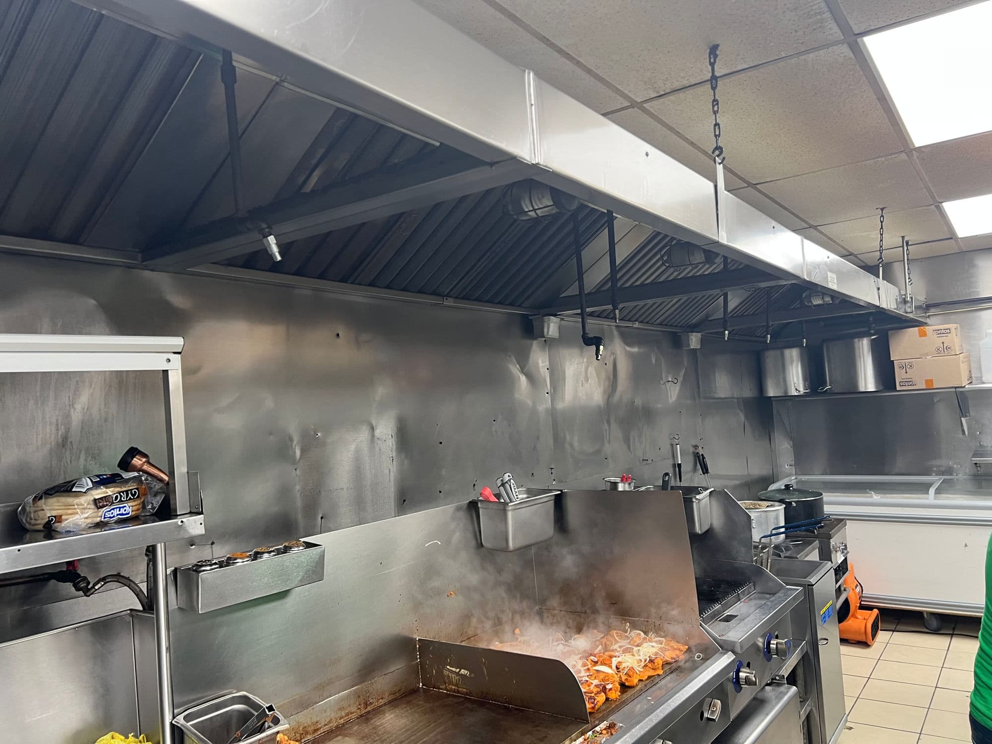 Stainless steel commercial kitchen exhaust hood over an active cooking line