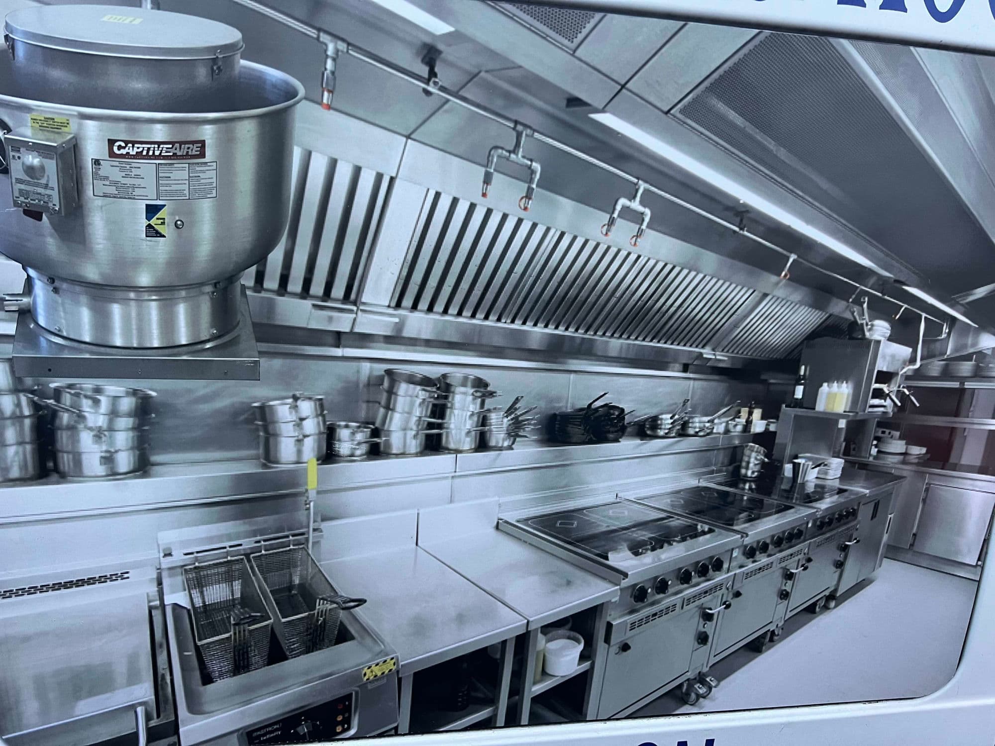 Stainless steel commercial kitchen with overhead exhaust hood in New York City